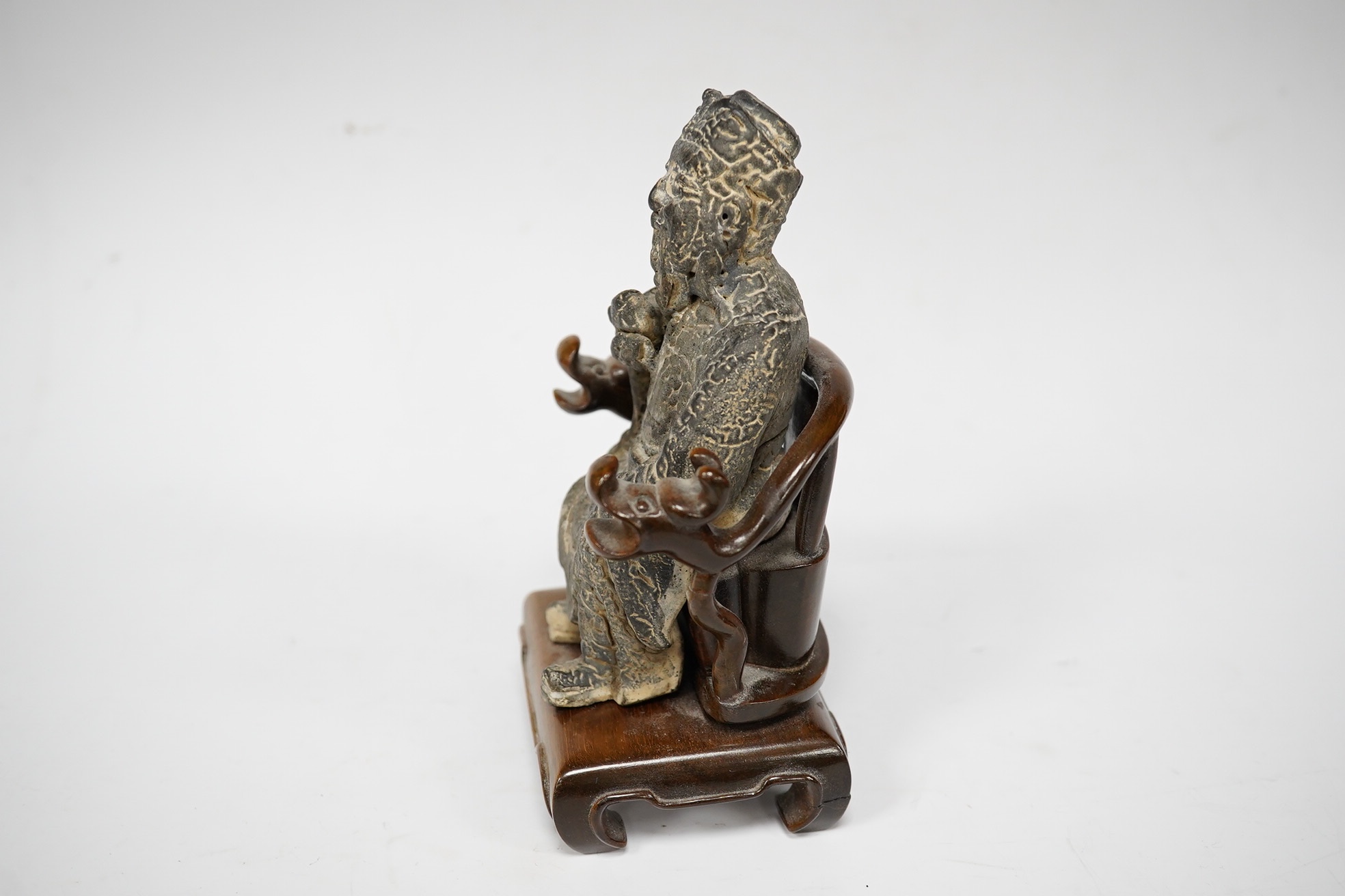 A Chinese grey pottery seated figure of a God, possibly Ming dynasty, seated on a later wood throne (with receipt of purchase from C C Tih Gallery, Hong Kong, 1968), 15cm high. Condition - fair